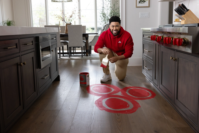 Jake from State Farm painting the State Farm logo on the kitchen floor