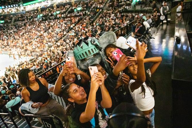 Sports fans taking selfies with Ellie the Elephant, the NY Liberty mascot