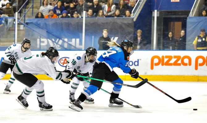 Natalie Spooner skating past Boston players to get to the puck