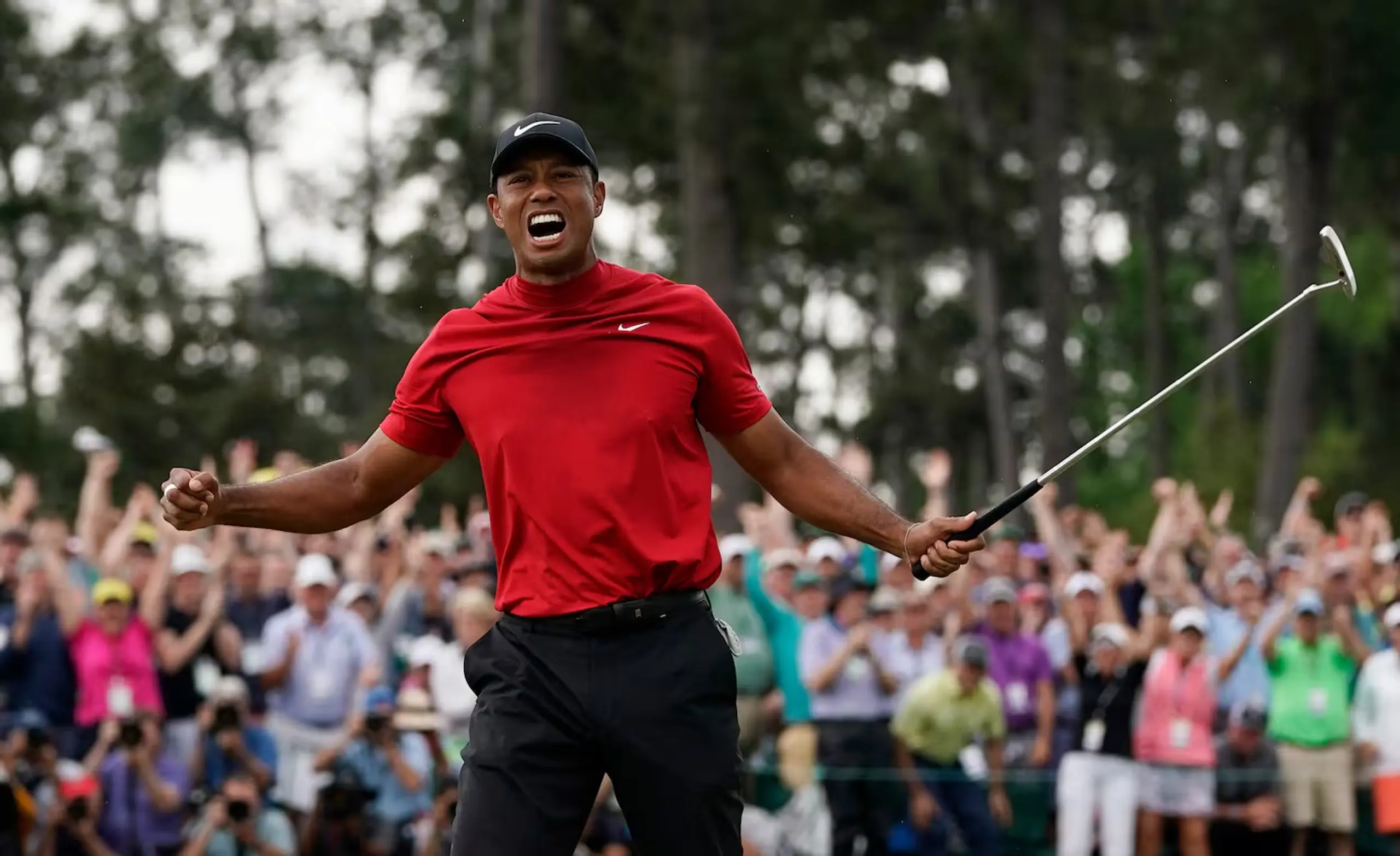 Golf legend Tiger Woods celebrates while wearing his iconic red Nike shirt.