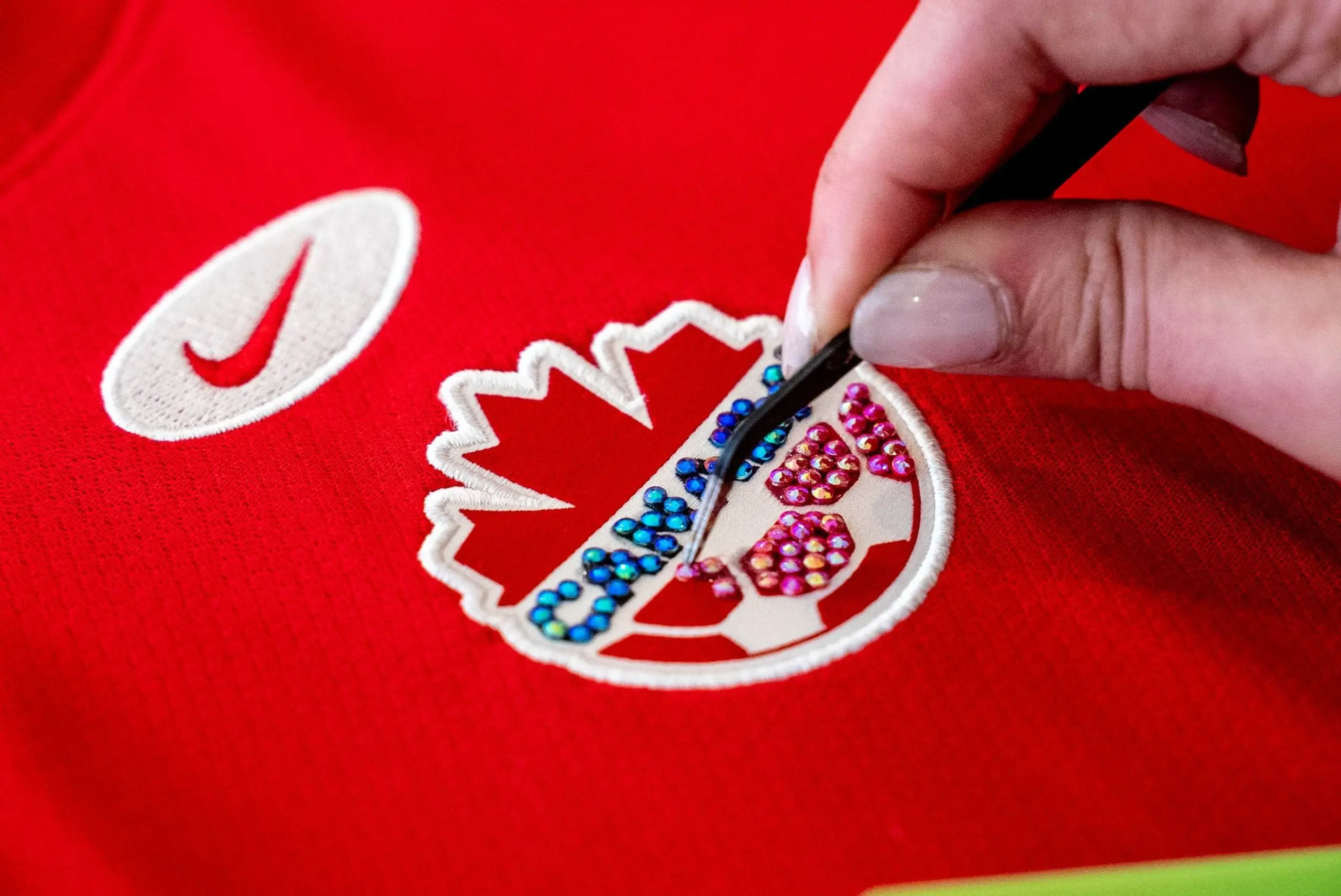 A creator adds rhinestones to their Team Canada jersey.