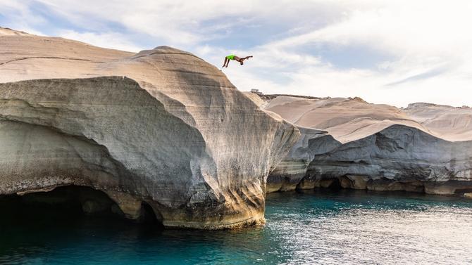 A person diving into a cliff into a body of water