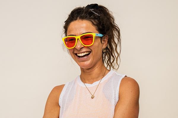A woman wearing sunglasses smiles.
