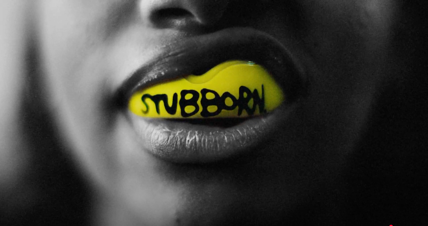 An image of a person wearing a mouthguard with the word "stubborn" printed on it.