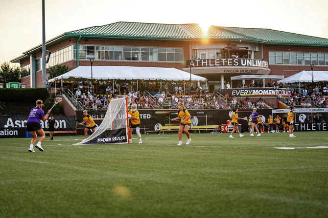 An action shot of an AU lacrosse game, with the stands in the background.