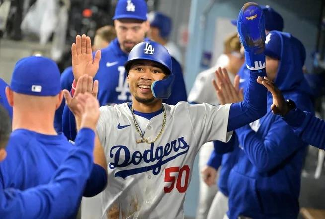 LA Dodger Mookie Betts high-fives his teammates in the dugout.