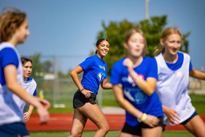 Evangeline Osieck smiling on the soccer field with her teammates