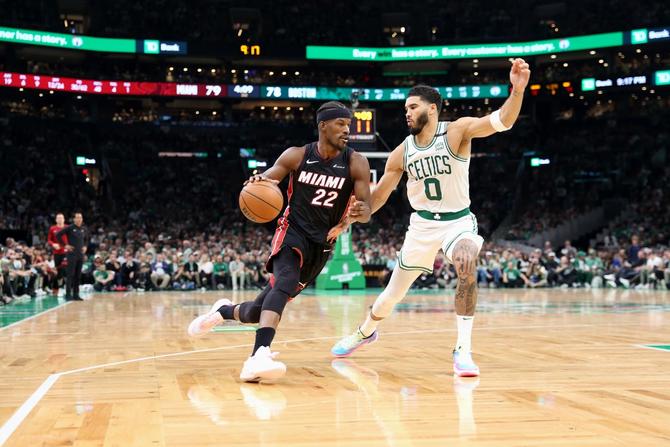 Jimmy Butler of the Miami Heat dribbles the ball while being defended by Boston Celtic Jaylen Brown.