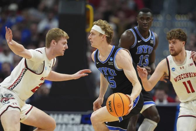 BYU guard Richie Saunders dribbles in between two defenders.