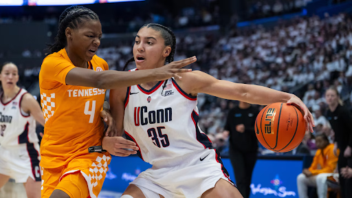 UConn’s Azzi Fudd dribbles the ball while being defended.