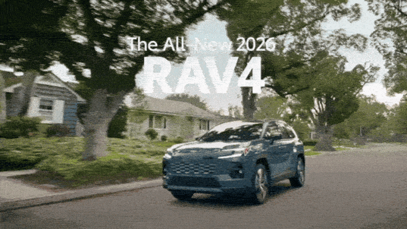 Blue 2026 Toyota RAV4 drives through tree-lined neighbourhood