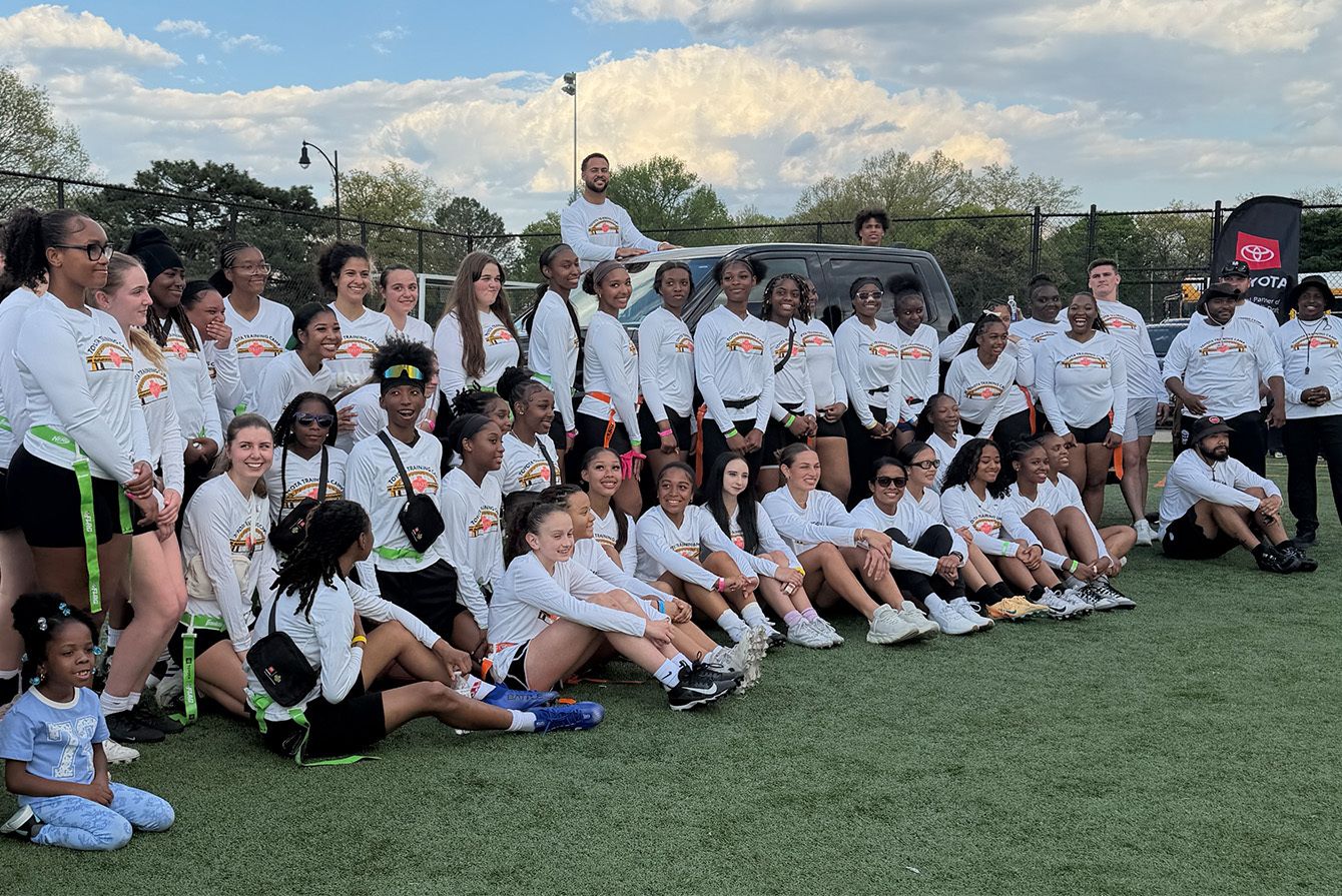 Group photo of participants from flag football camp posing on the field