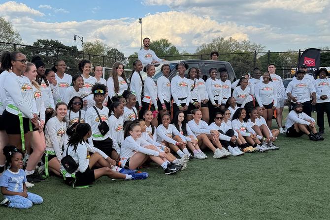 Group photo of participants from flag football camp posing on the field