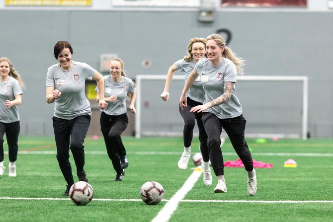 A team running after soccer balls