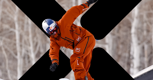 Snowboarder glides on board in front of new X Games logo.