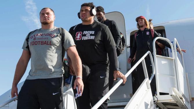 Stanford football players step off a plane.