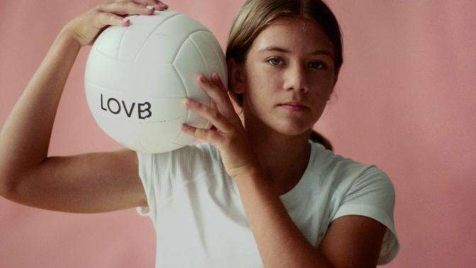 A young athlete poses with a LOVB volleyball.