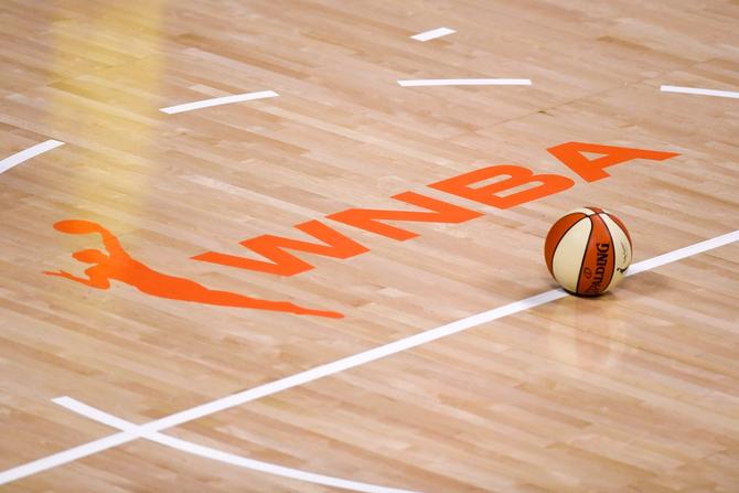 General view of the WNBA logo painted on the court with a basketball laying on the floor.