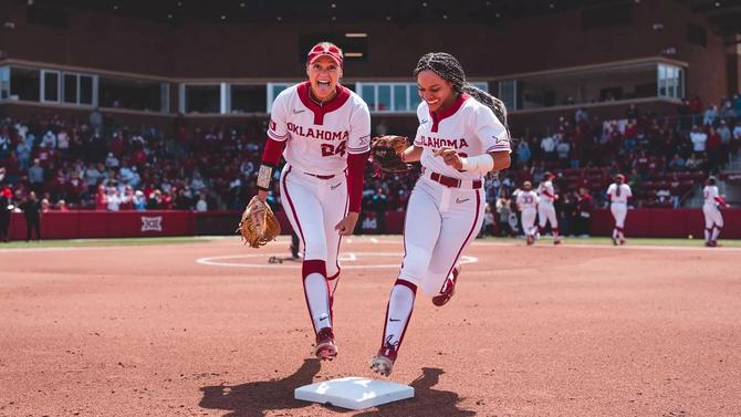 No. 2 Oklahoma softball outfielders Jayda Coleman and Rylie Boone smile while racing across second base to their positions during a home game.