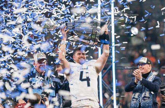 Quarterback Nick Arbuckle of the Toronto Argonauts lifts the Grey Cup above his head as confetti falls.