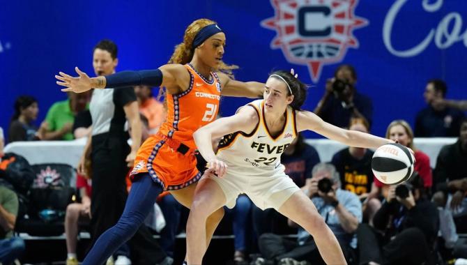 The Indiana Fever's Caitlin Clark dribbles the ball while being guarded by the Connecticut Sun's DiJonai Carrington.