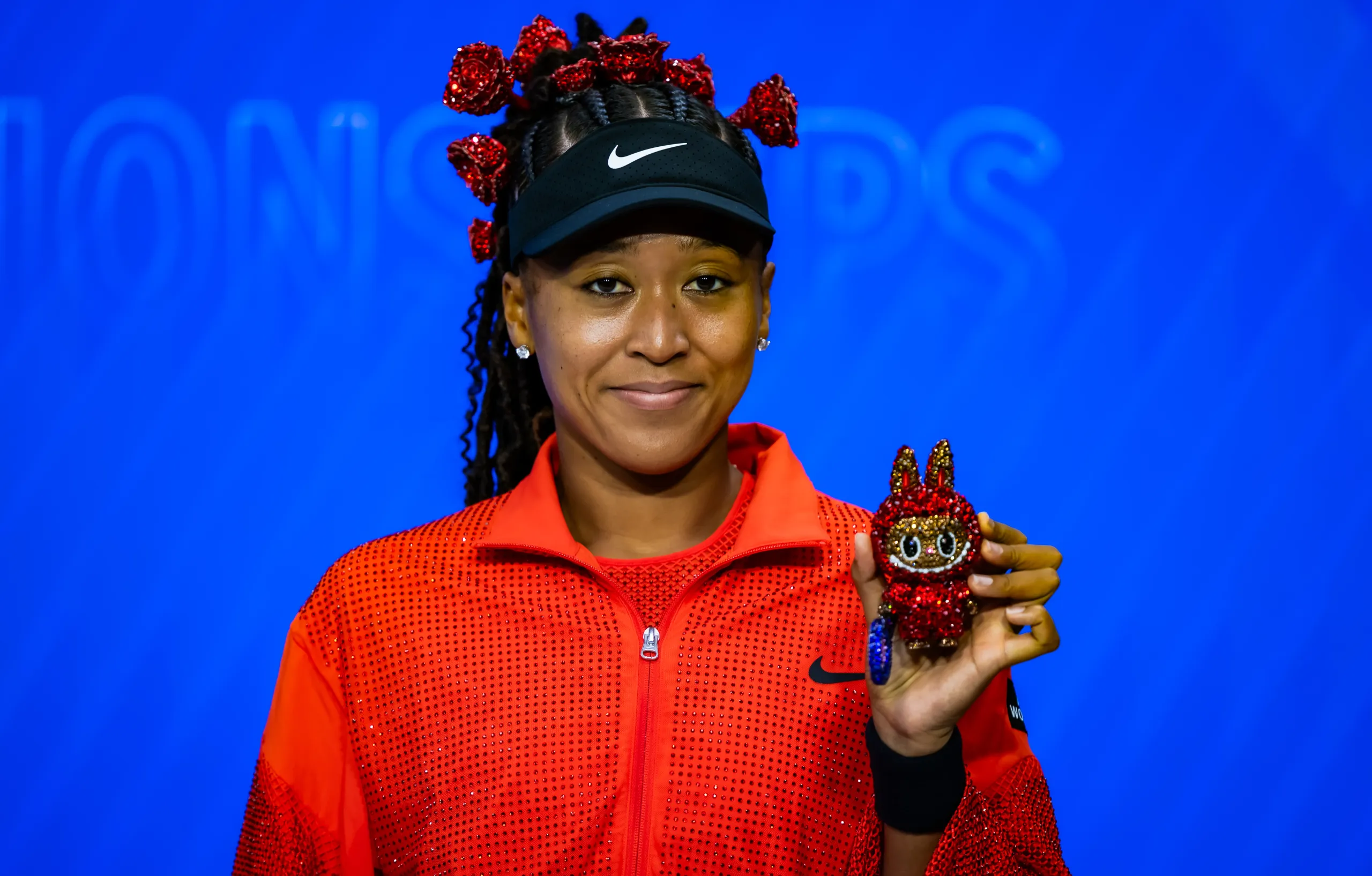 Naomi Osaka shows off Billie Jean Bling at a press conference. 
