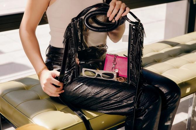 A person holding out a handbag while sitting down
