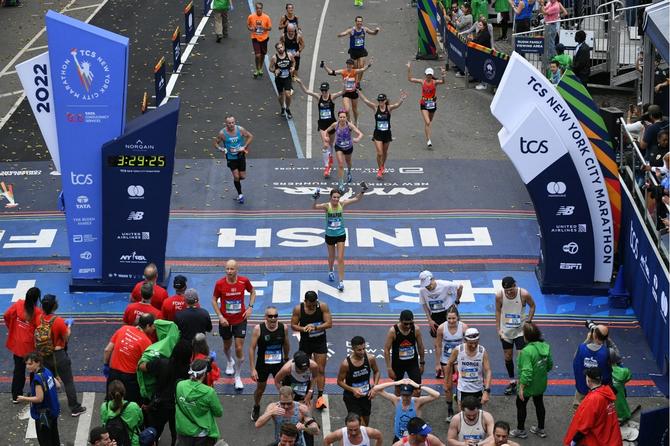 Participants run across the finish line at the NYC Marathon