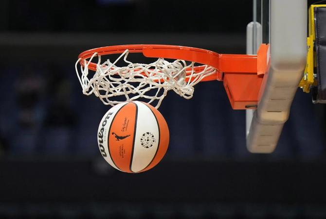 A photo of an official WNBA basketball going through the mesh.
