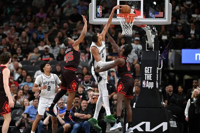San Antonio Spur Victor Wembanyama dunks on two Chicago Bulls defenders.