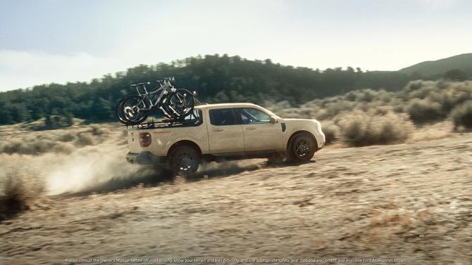 A white Ford Maverick driving on a dirt road