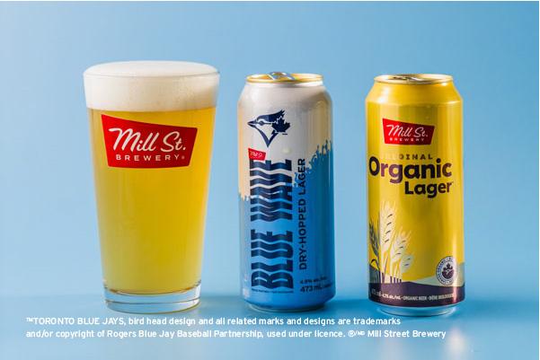 A glass of beer and two cans of beer lined up in a row
