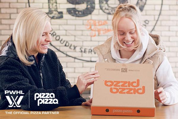 Two women smiling and sharing a box of Pizza Pizza