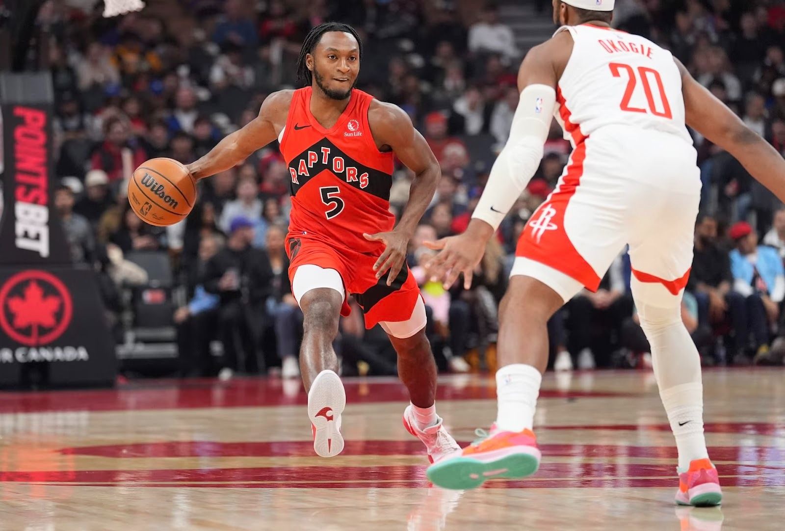 Toronto Raptor Immanuel Quickly dribbles while being defended by a Houston Rocket defender.