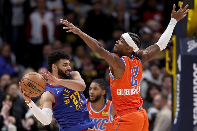 Jamal Murray #27 of the Denver Nuggets is guarded by Shai Gilgeous-Alexander #2 of the Oklahoma City Thunder in the fourth quarter at Ball Arena