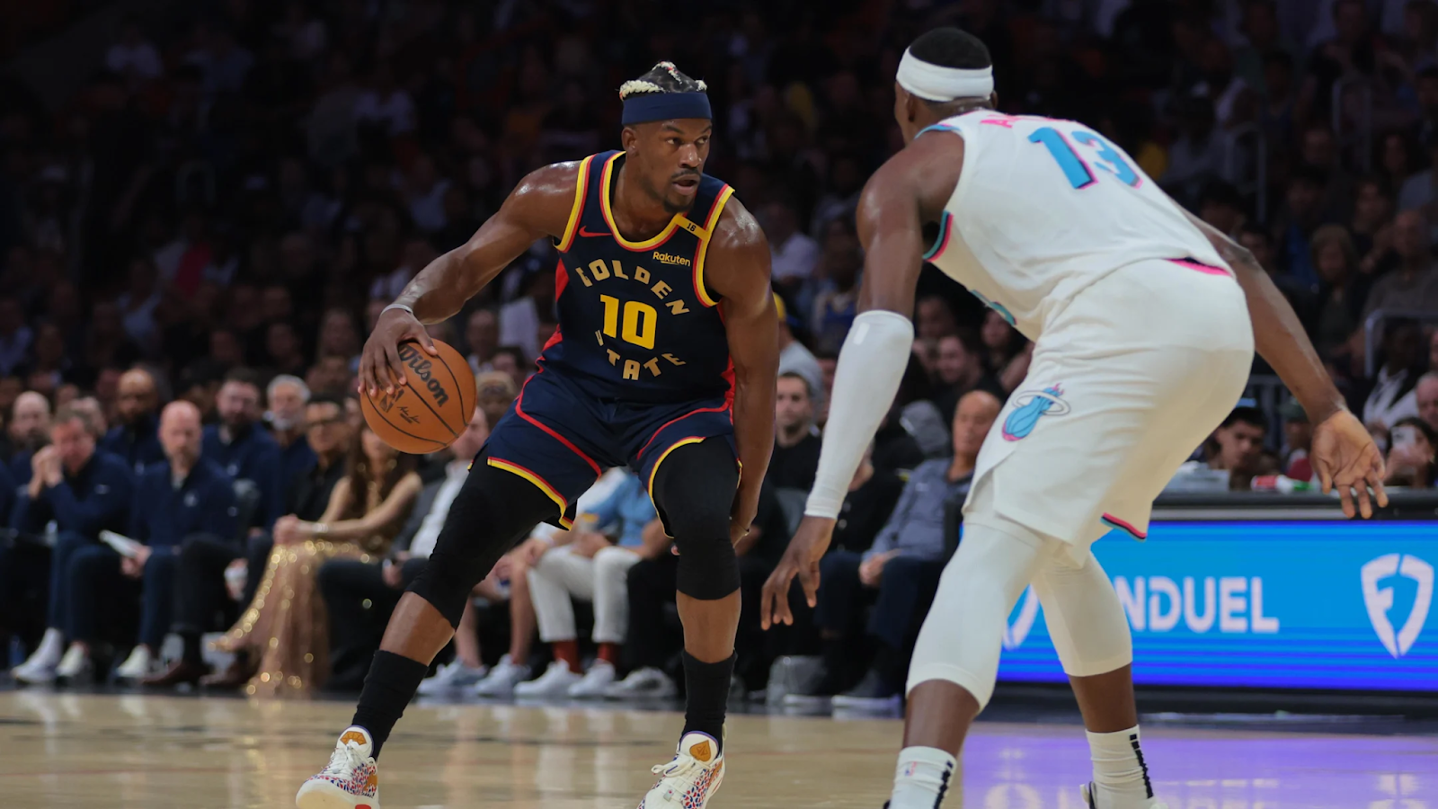 Golden State Warrior Jimmy Butler dribbles while being defended by Miami Heat forward Bam Adebayo.