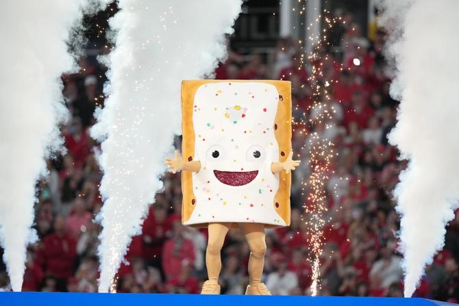 A giant Strawberry Pop Tart stands on a stage as fireworks and smoke go off behind it.