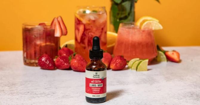 A bottle of Lazarus Naturals next to a cocktail on a counter