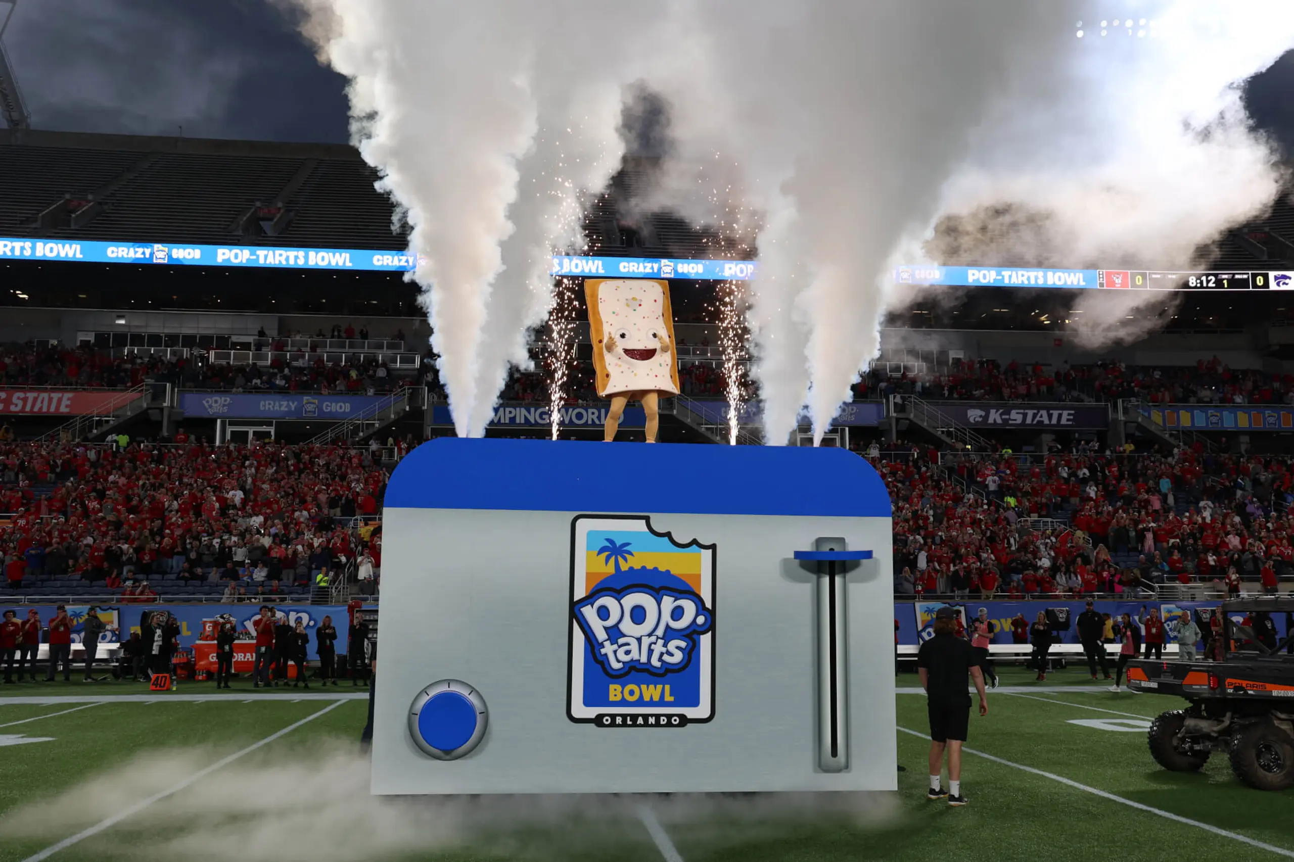 The Pop-Tart Bowl edible mascot is lowered into a giant toaster on the field.