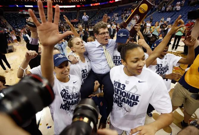 UConn women’s basketball head coach Geno Auriemma celebrates with his players after winning the 2013 national championship.