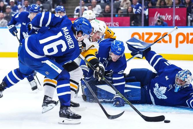Toronto Maple Leafs forward Mitch Marner plays the puck in front of the net against the Pittsburgh Penguins.