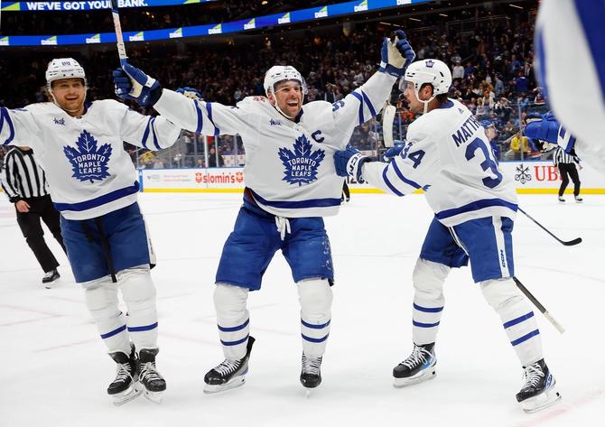 John Tavares #91 of the Toronto Maple Leafs (C) celebrates his assist and 1000th NHL point against the New York Islanders