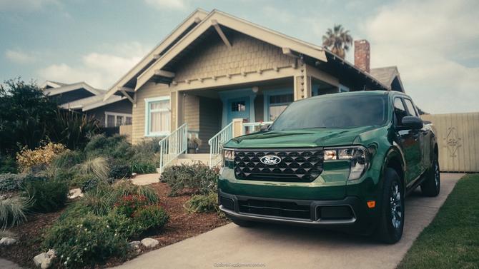 A green Ford truck parked outside a house