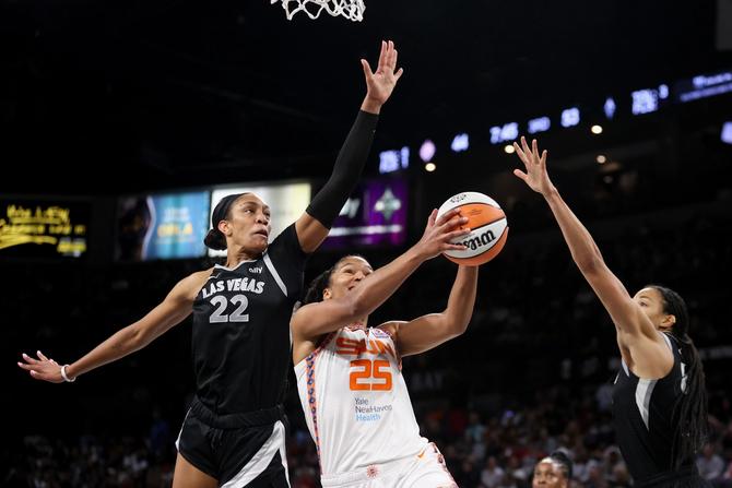 Alyssa Thomas of the Connecticut Sun drives in for a layup between Las Vegas Aces A'ja Wilson and Kiah Stokes.