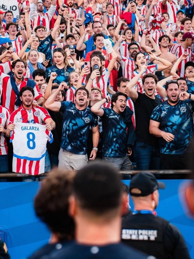 Players from the Paraguay national team walk towards celebrating fans.