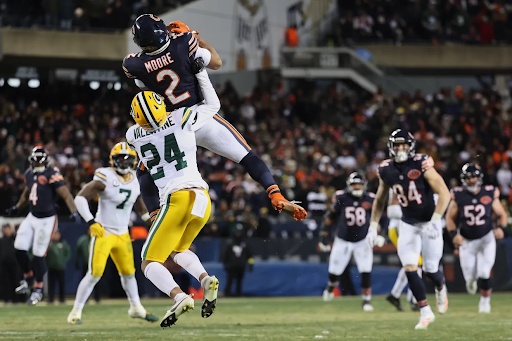 Chicago Bears wide receiver D.J. Moore makes a catch in overtime while being tackled by Green Bay Packer Carrington Valentine.
