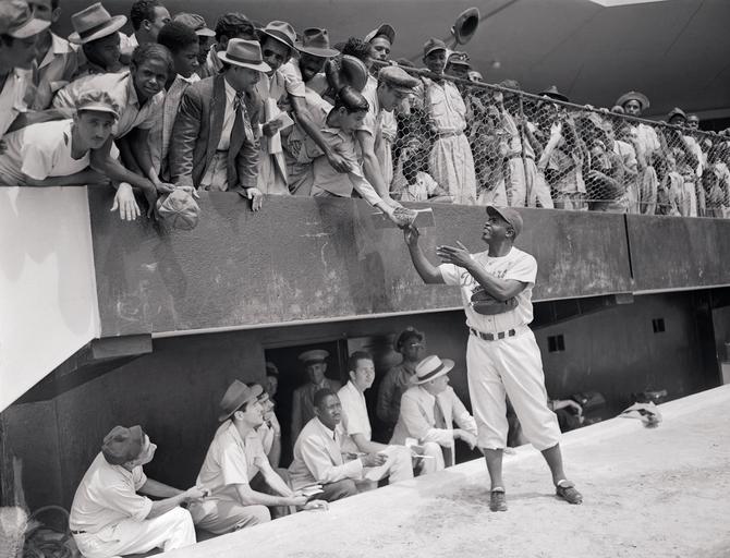 Jackie Robinson signing autographs on the field.
