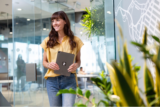 A woman smiling while holding a tablet