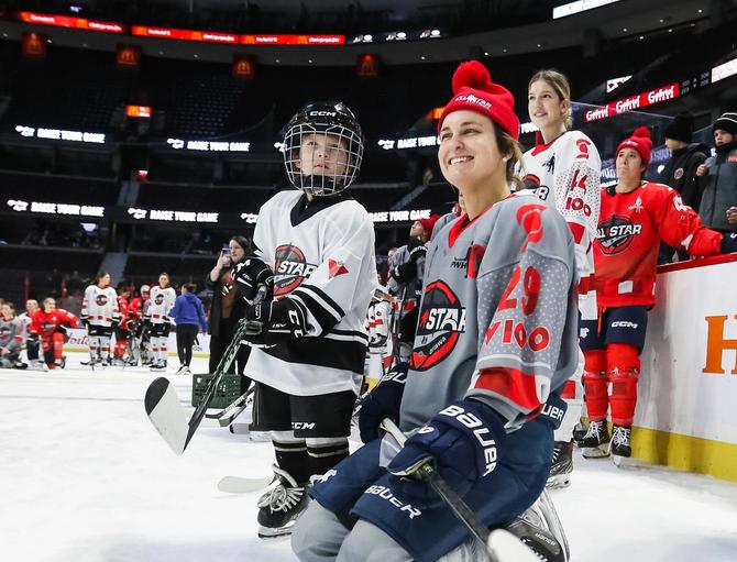 Marie-Philip Poulin smiling on the ice with kids