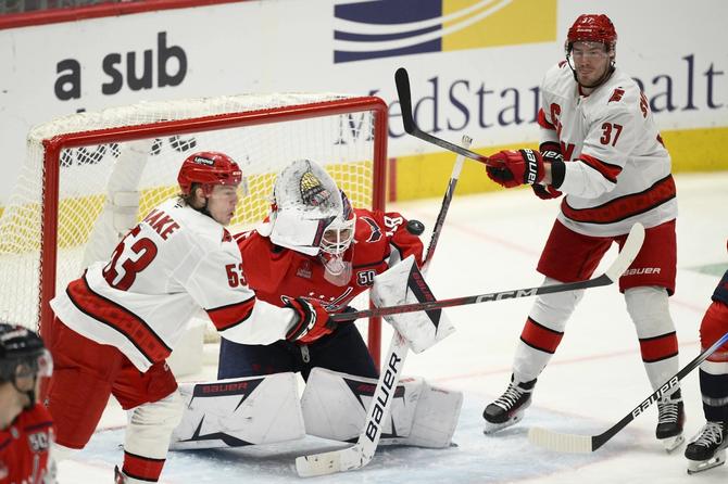 The Carolina Hurricanes rush Washington Capitals goaltender Logan Thompson.